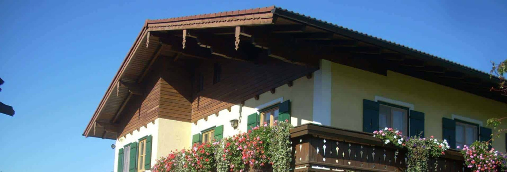 Blick auf das Haus der Familie Putz mit Blumenkästen und blauen Himmel im Salzburgerland.